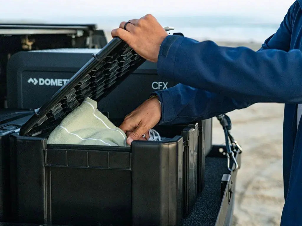 Person opening a black Front Runner Wolf Pack Pro Storage Box with a white bag inside.