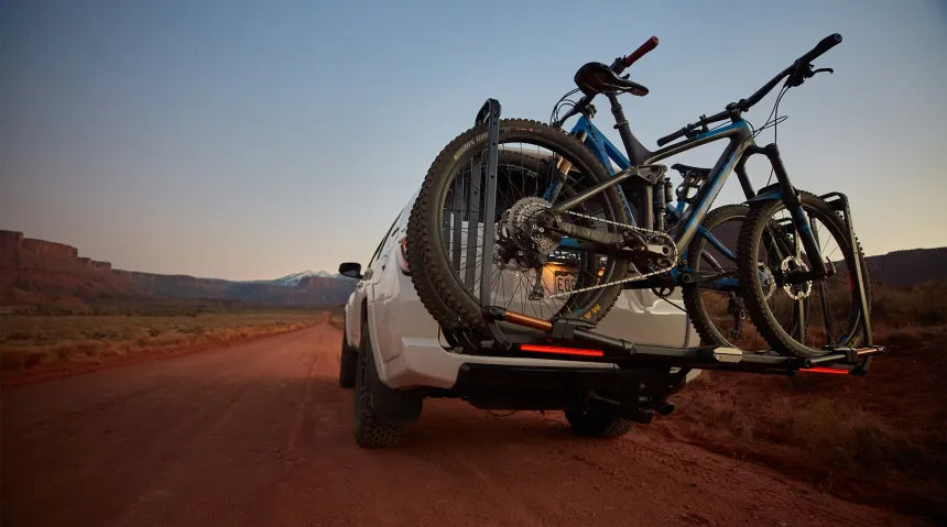 Shot of the Kuat Piston Pro X loaded with bikes on a dirt road. 