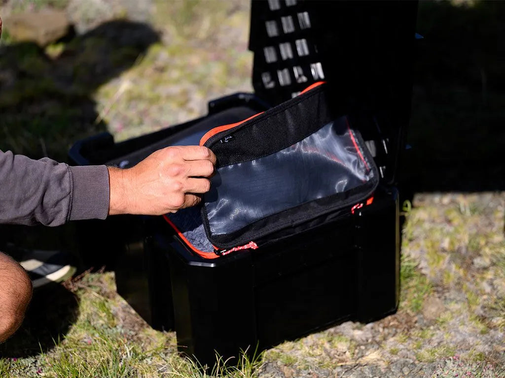 Person opening a black tool box with transparent pouches outdoors